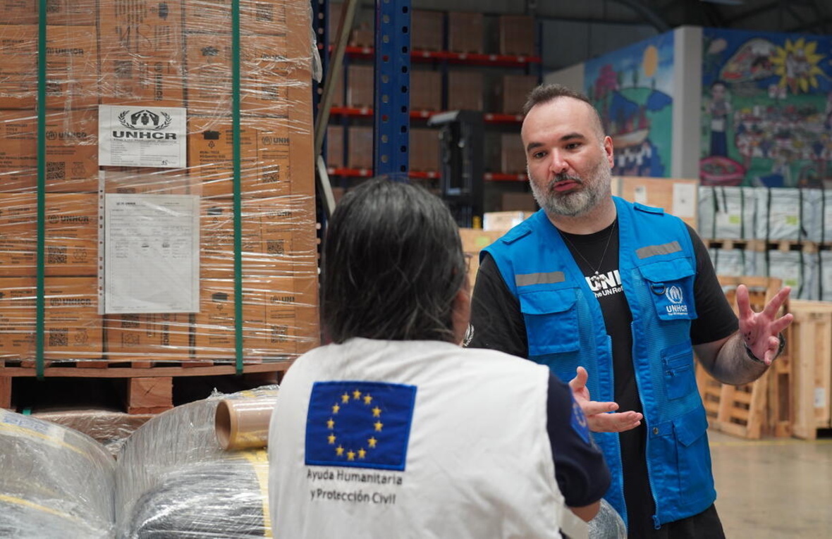 UNHCR Supply Associate and EU-ECHO staff talking inside a UNHCR warehouse