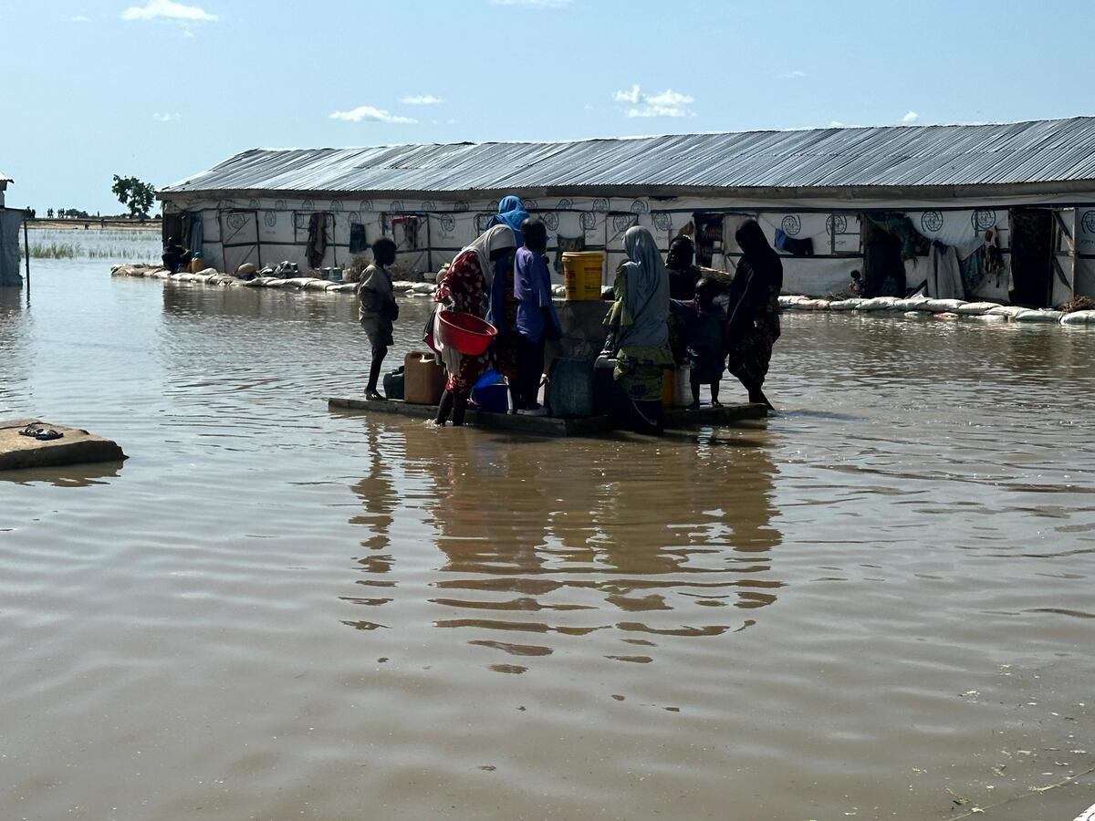 Des femmes et des enfants se rassemblent autour d'un point d'eau potable entouré par les eaux de crue.