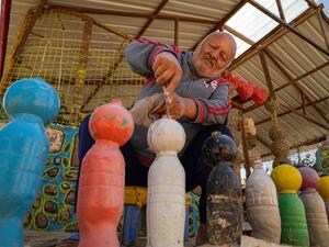 Un homme crée des bollards à partir de bouteilles en plastique peintes