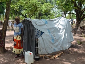 Une femme se tient devant un abri, un canon à eau à côté d'elle.