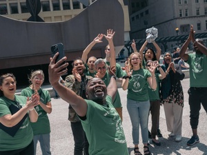 Un groupe de personnes souriantes et enthousiastes prend un selfie à Chicago lors des célébrations de la Journée mondiale des réfugiés. 
