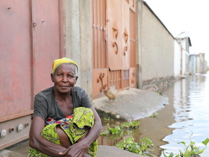 Une femme est assise par terre dans un quartier inondé.