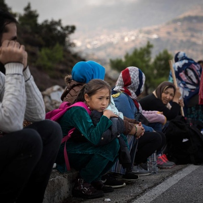 Des hommes, des femmes et des enfants attendent sur le bord de la route en Grèce.
