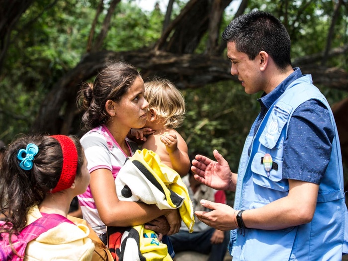 Une femme avec deux jeunes enfants échange avec un employé du HCR, en Colombie.