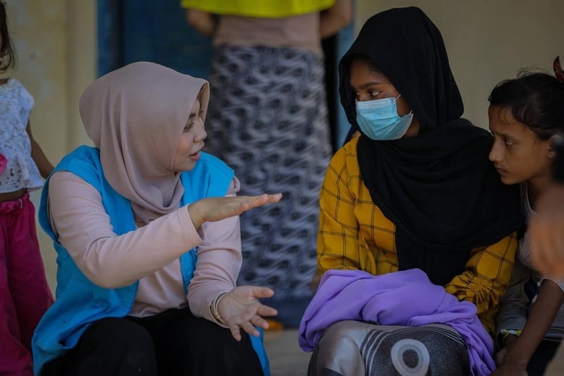 Une employée du HCR s'entretient avec deux réfugiés rohingyas sur un site dans le sud d'Aceh.