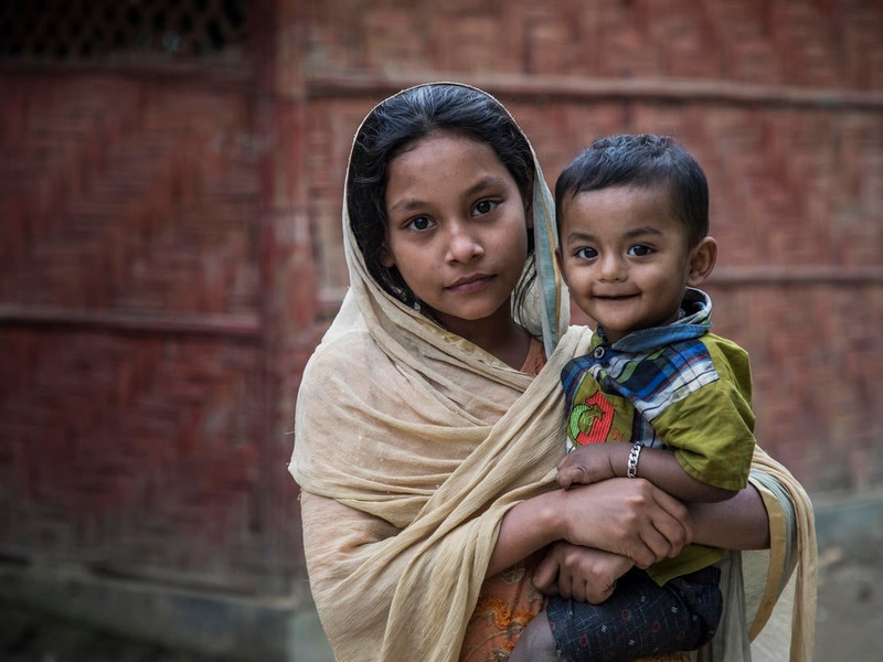 Une jeune fille Rohingya tient son petit frère dans ses bras. 