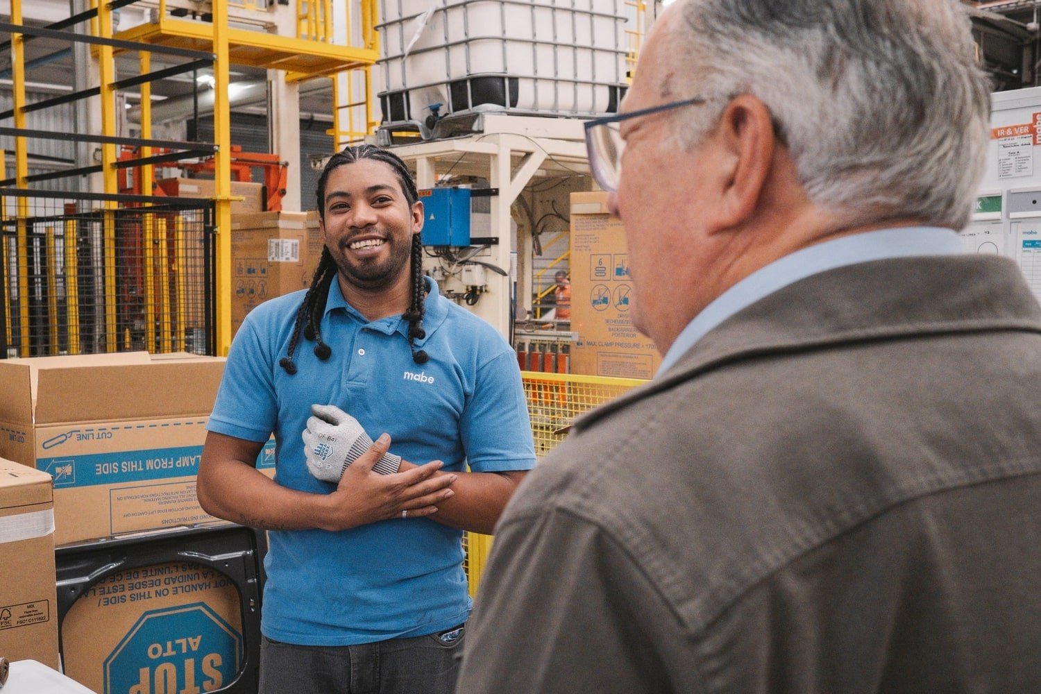 A man in a blue polo shirt smiles at a man in the foreground