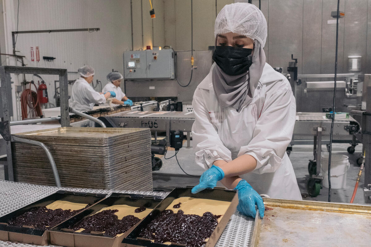 Un employé prépare une plaque de pâte à cuire.