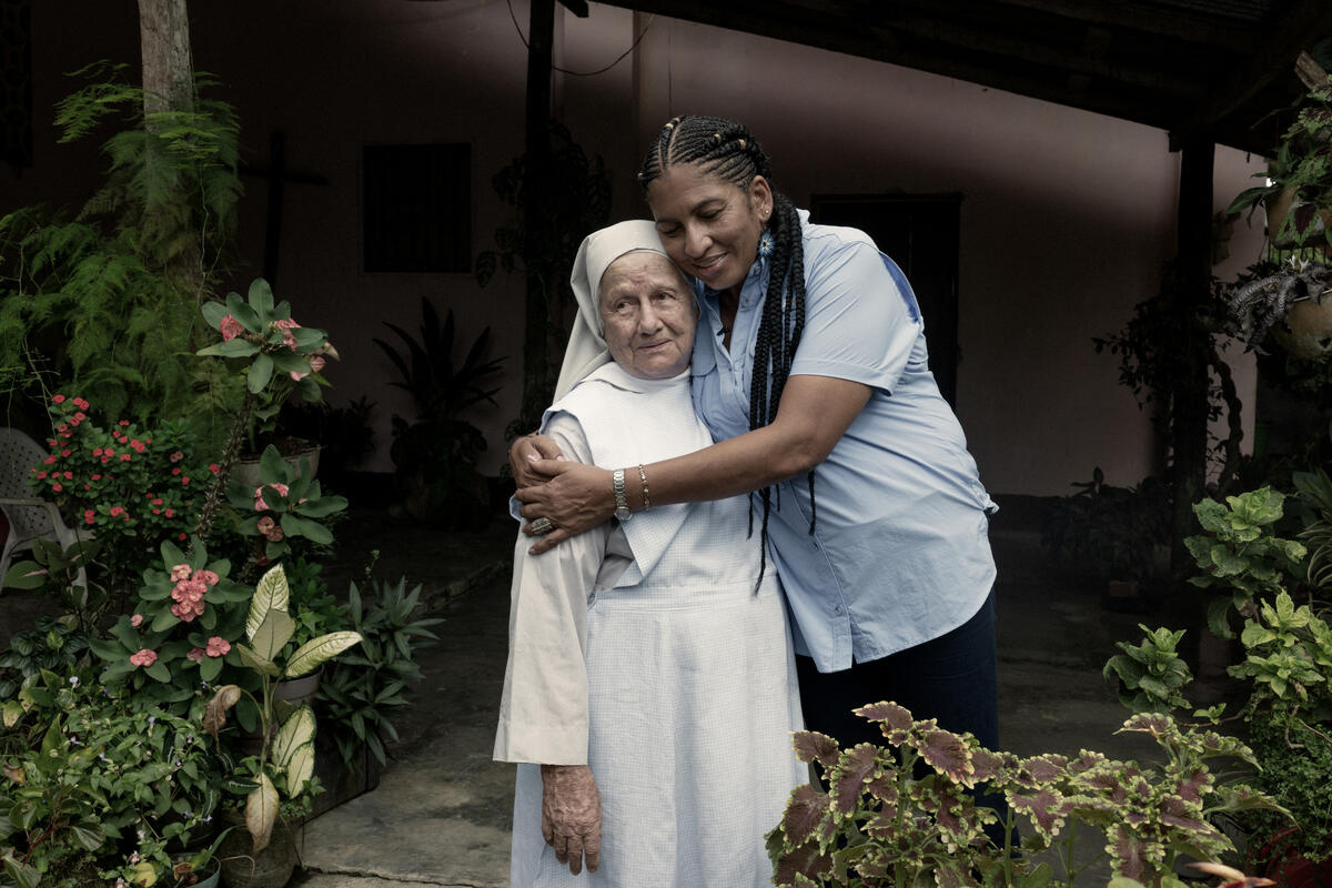 Une femme serre dans ses bras une religieuse vêtue d'un habit blanc.