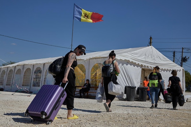 Des réfugiés ukrainiens portant leurs bagages sont accueillis dans un centre de transport