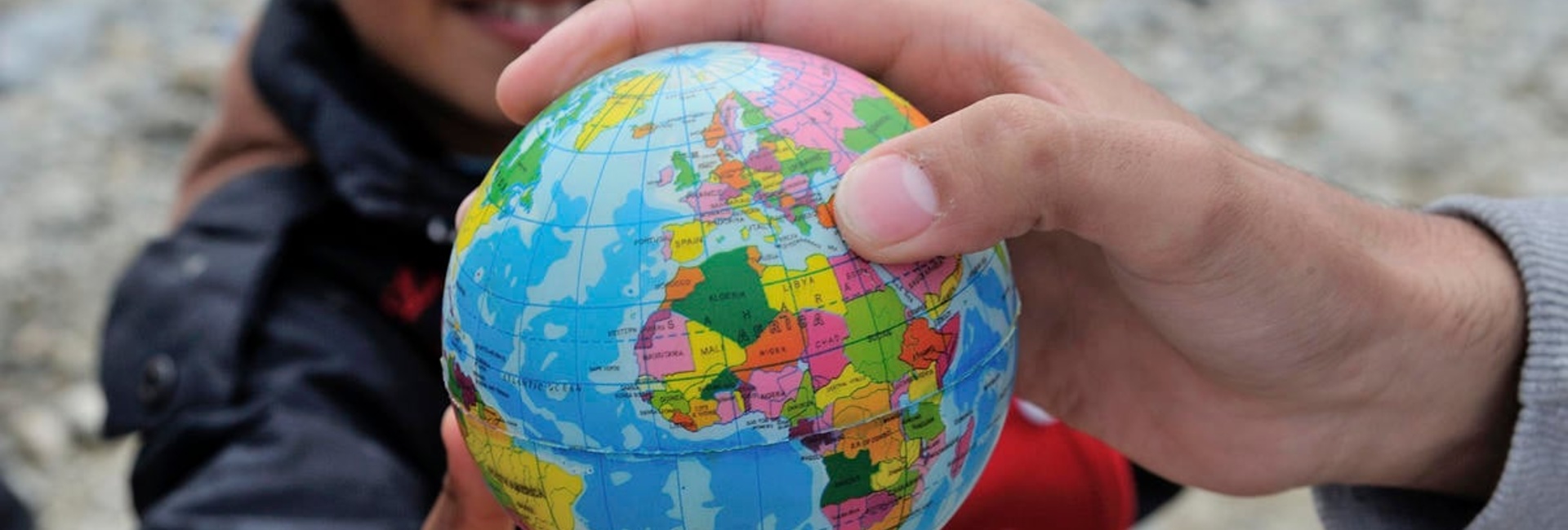 Un jeune garçon tient une petite mappemonde.