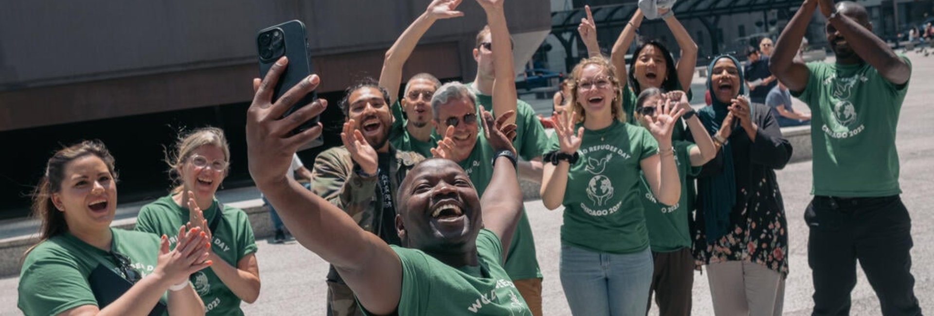Un groupe de personnes souriantes et enthousiastes prend un selfie à Chicago lors des célébrations de la Journée mondiale des réfugiés. 