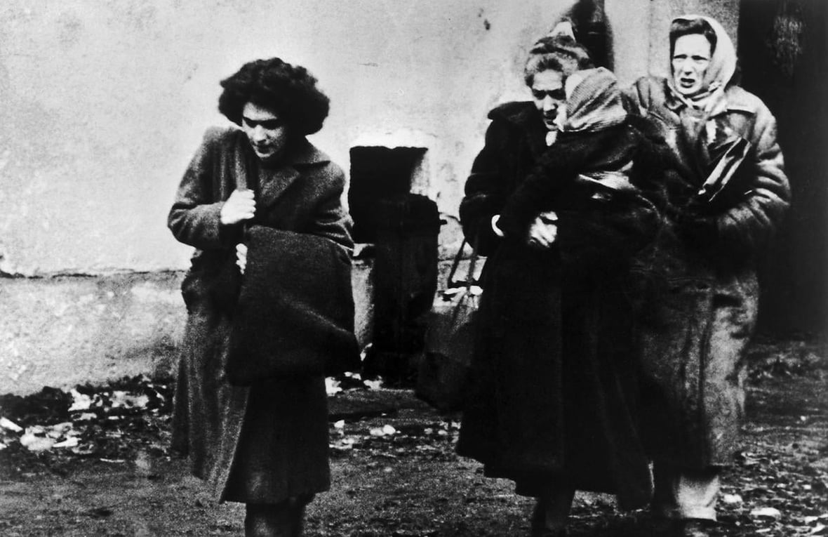 Photo en noir et blanc montrant trois femmes et un enfant arrivant dans un camp de réfugiés en Autriche.