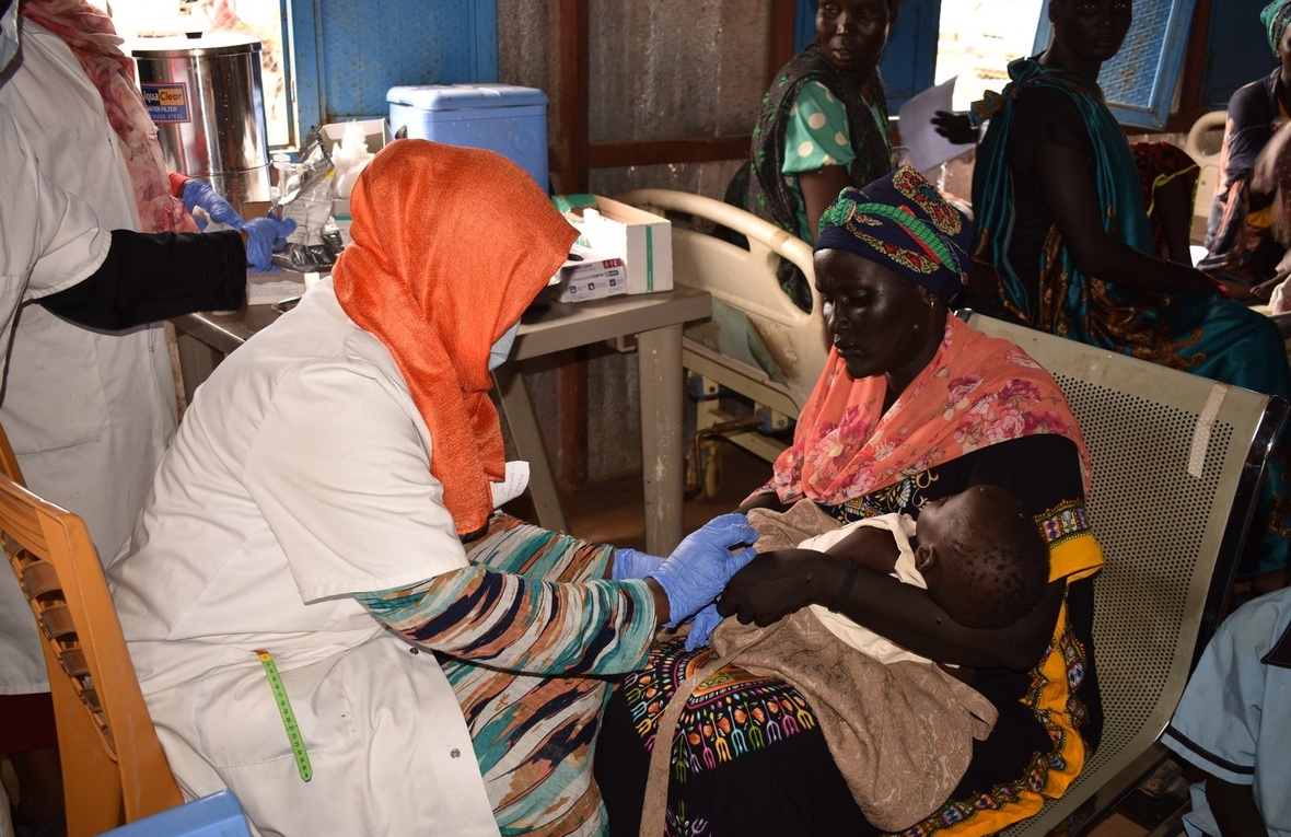 Une infirmière s'occupe d'un bébé avec sa mère dans une clinique au Soudan.