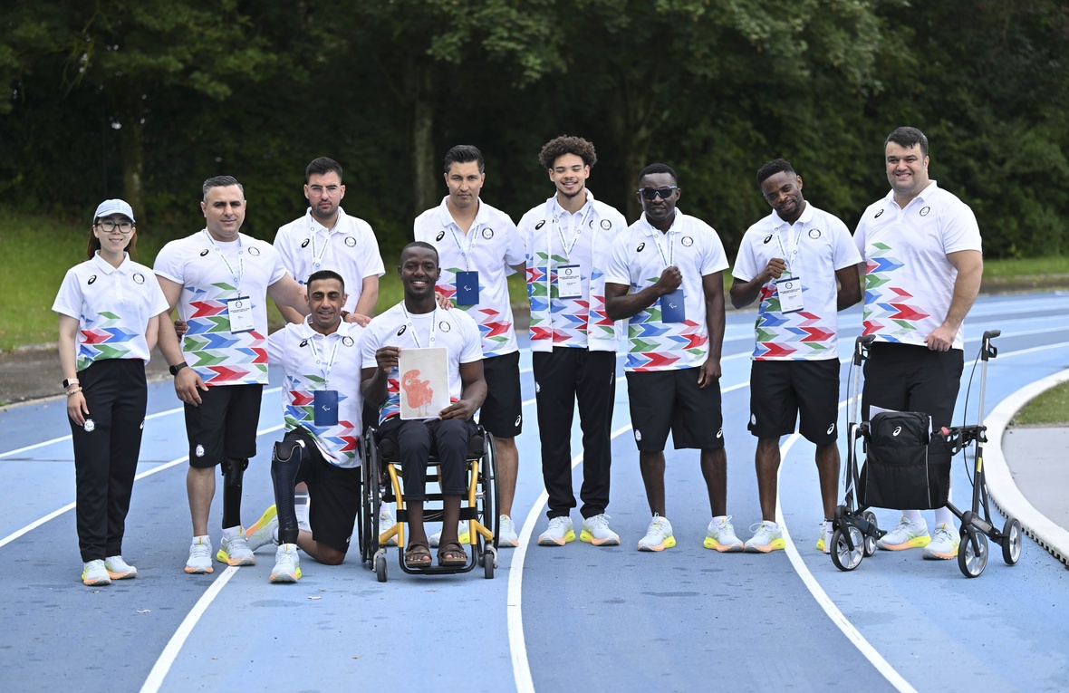 Des athlètes en uniformes assortis posent pour une photo de groupe sur une piste de course.