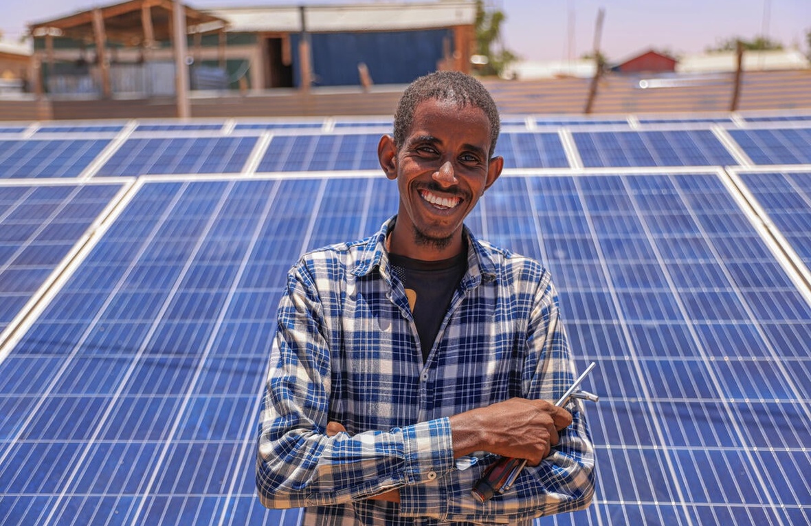 Un homme sourit devant un mini-réseau solaire.