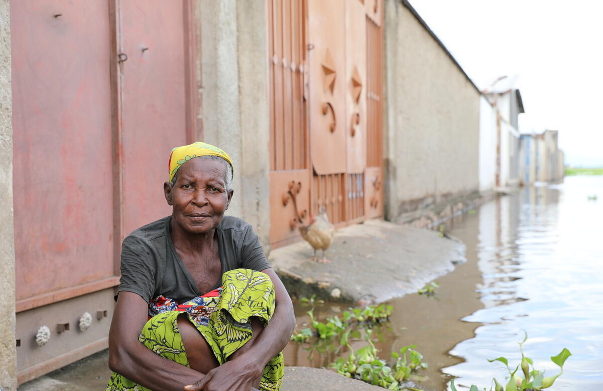 Une femme est assise par terre dans un quartier inondé.