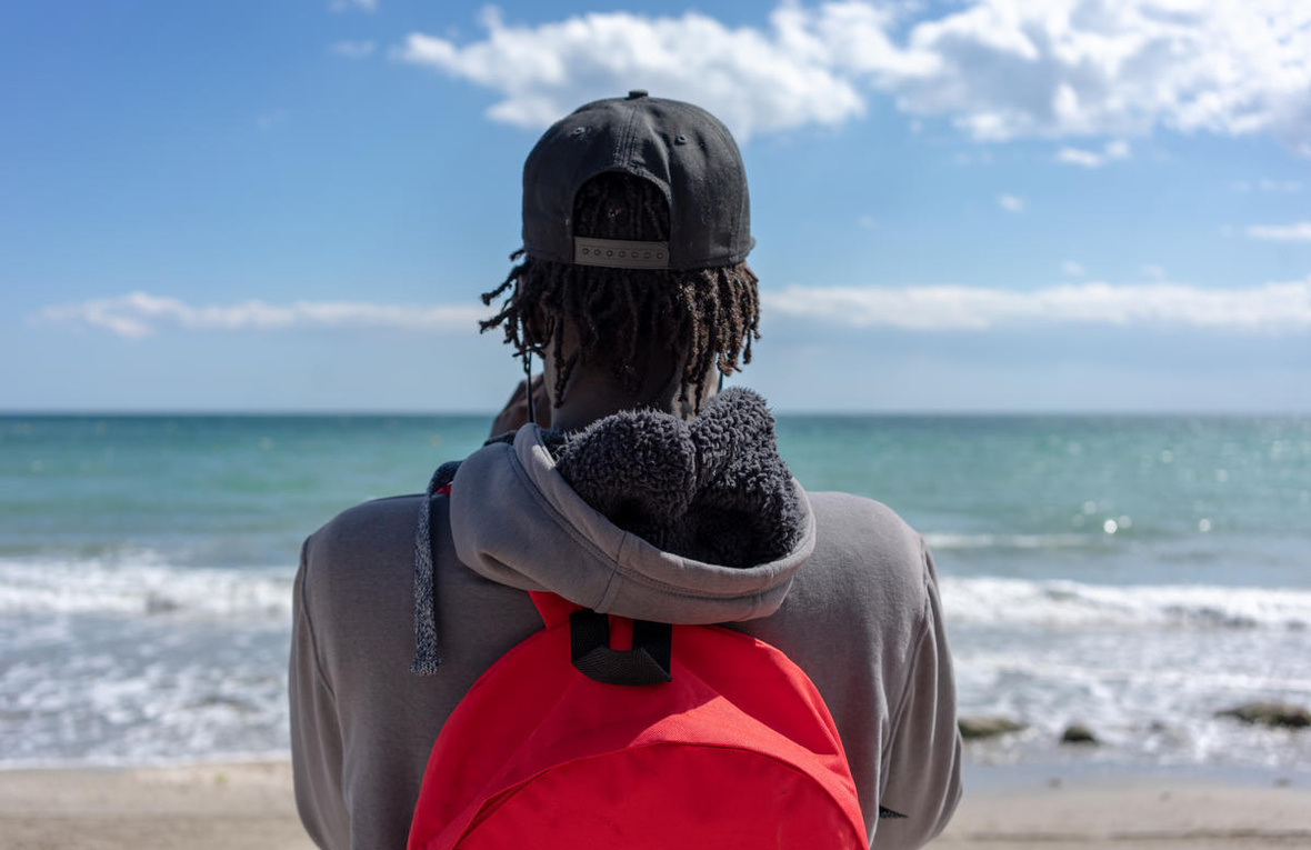 Un homme portant un sac à dos regarde la mer