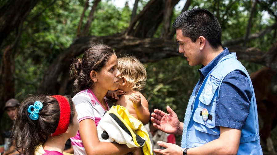 Une femme avec deux jeunes enfants échange avec un employé du HCR, en Colombie.