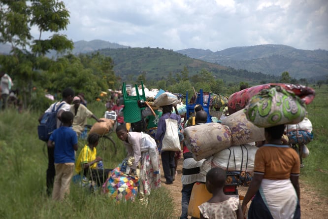 Congolese families walking with their belongings on their heads and backs
