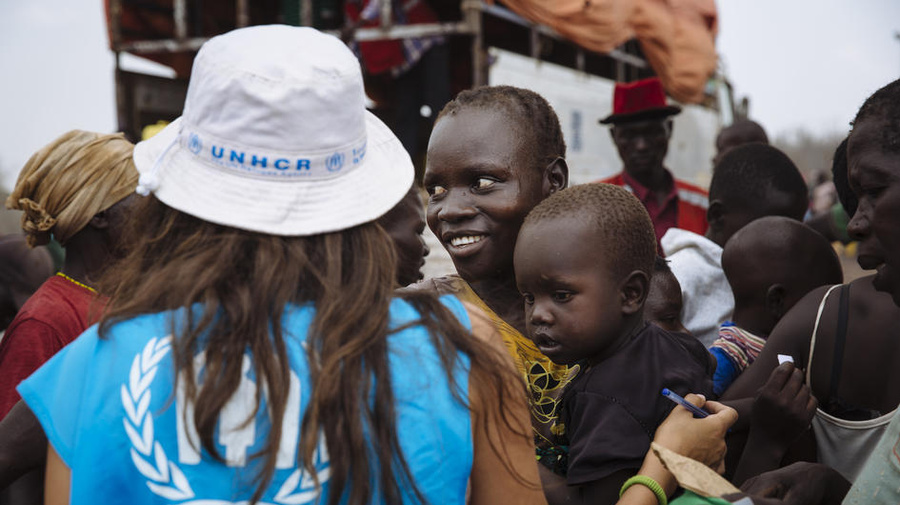 South Sudanese refugee Kiden Sam, 28, centre, carries her five-year-old Yukan Stephen as she waits to board a truck heading for the recently established Imvepi settlement, at the Imvepi Reception Centre, Arua District, Northern Region, Uganda.