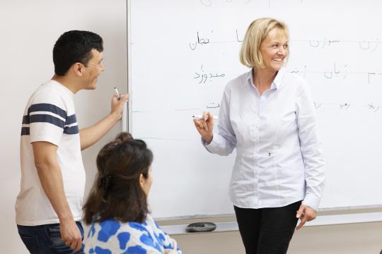 Teacher interacting with student near white board