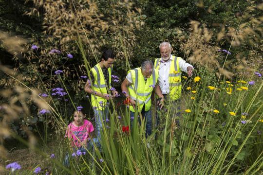 Adults wearing reflective jacket and a young kid in a garden