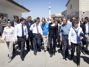 Angelina Jolie (in black) and António Guterres (next to her in blue open neck shirt) tour a camp housing thousands of Syrian refugees in Turkey.