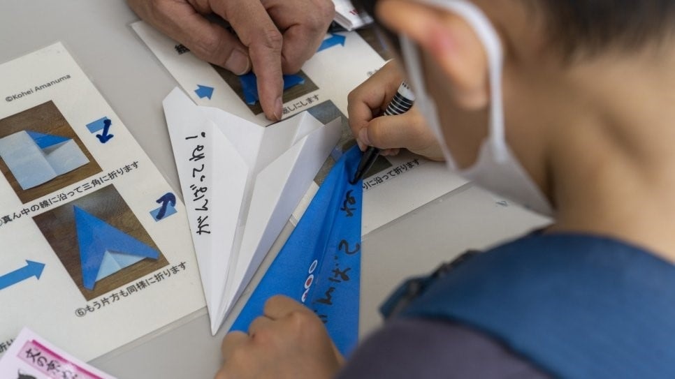 A pupil writes messages to the Refugee Paralympic Team on paper airplanes in Bunkyo, Japan. © UNHCR/Taro Karibe