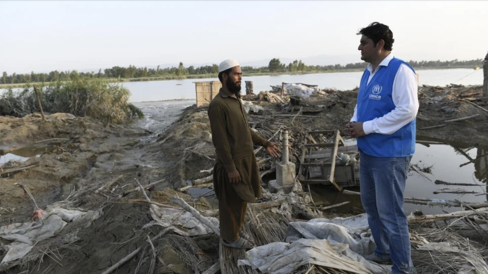 Saleem Khan talks to a UNHCR staff member. His family have received a tent but with their crops destroyed, they lack money to rebuild their home. © UNHCR/Usman Ghani