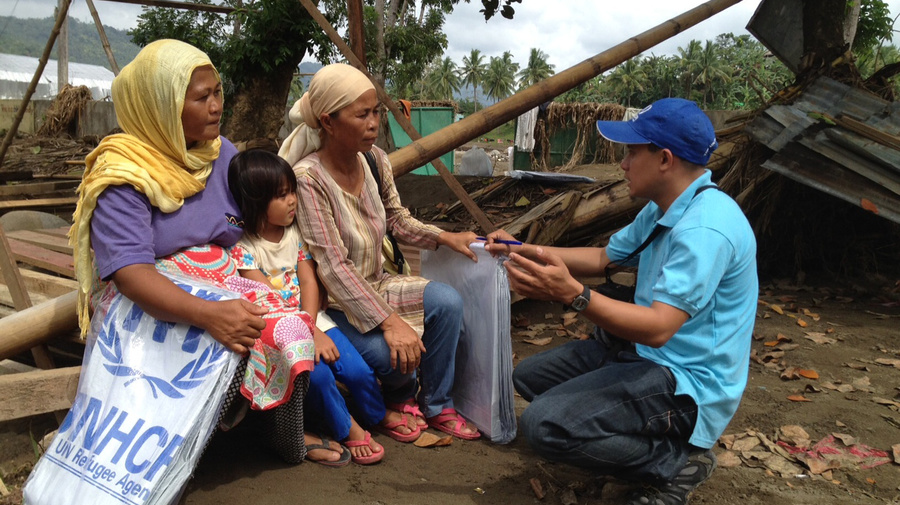 UNHCR's Rasul Kulat with beneficiaries Imelda Angud and Dairi Bansil in the ruins of Bansil's house in Mandulog village, northern Mindanao island.