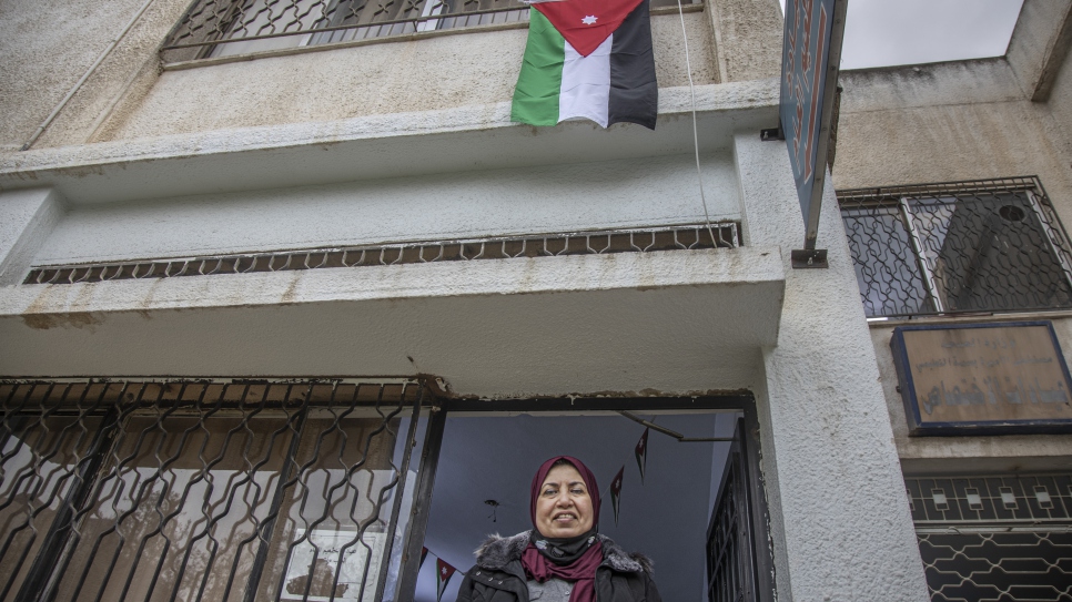 Raia AlKabashi stands under the flag of Jordan outside the health centre in Irbid where she received her COVID-19 vaccine. © UNHCR/Jose Cendon