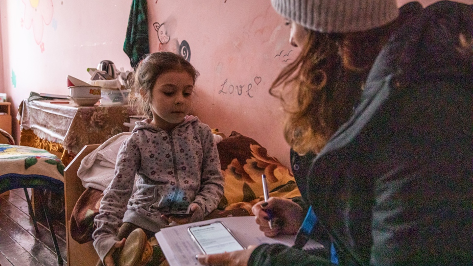 A UNHCR staff member speaks to Milana in her family’s room. © UNHCR/Igor Karpenko