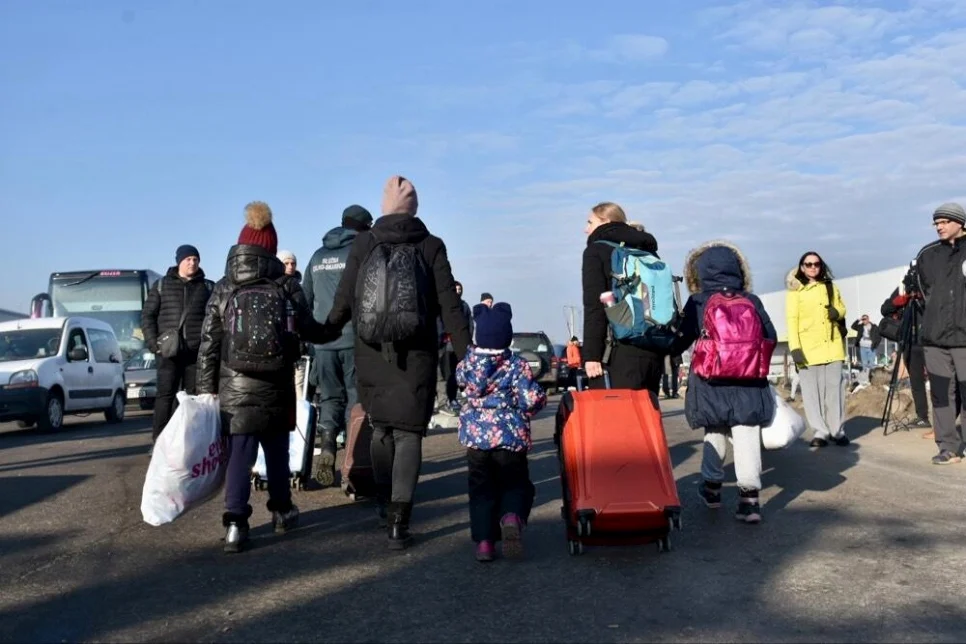 Families carry their belongings through the Zosin border crossing in Poland after fleeing Ukraine. © UNHCR/Chris Melzer