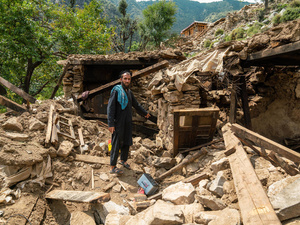 Seorang laki-laki menunjuk ke arah reruntuhan pasca gempa