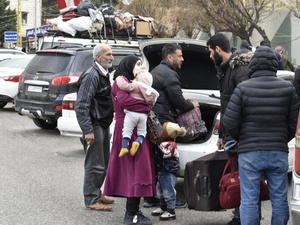 People gather at the back of a parked car at the Masnaa border point in Lebanon, waiting to cross into Syria