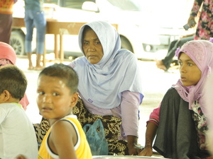 A small group of women and children sit on the floor.