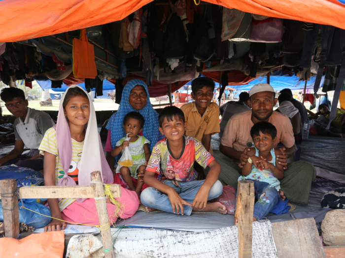 Refugee families consists of a man, a woman, three boys, and two girls are sitting inside a shelter in Aceh