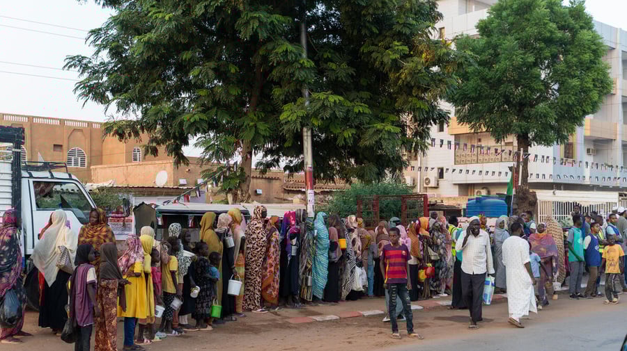 Keluarga pengungsi dari El Fasher berbaris untuk menerima bantuan makanan