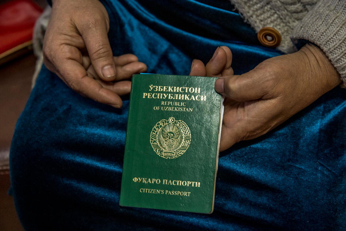 Close up of a woman's hands holding her invalid Uzbeck passport.