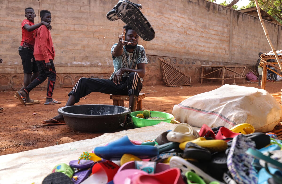 A Sudanese man washes sandals and throws them into a pile