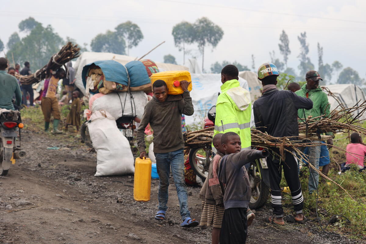 Families walk and ride, carrying their belongings, fleeing fighting in North Kivu.