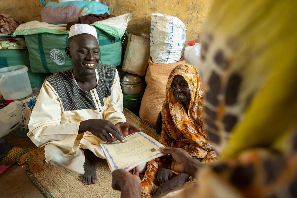 A young man points to some certificates that a woman is holding out to him.