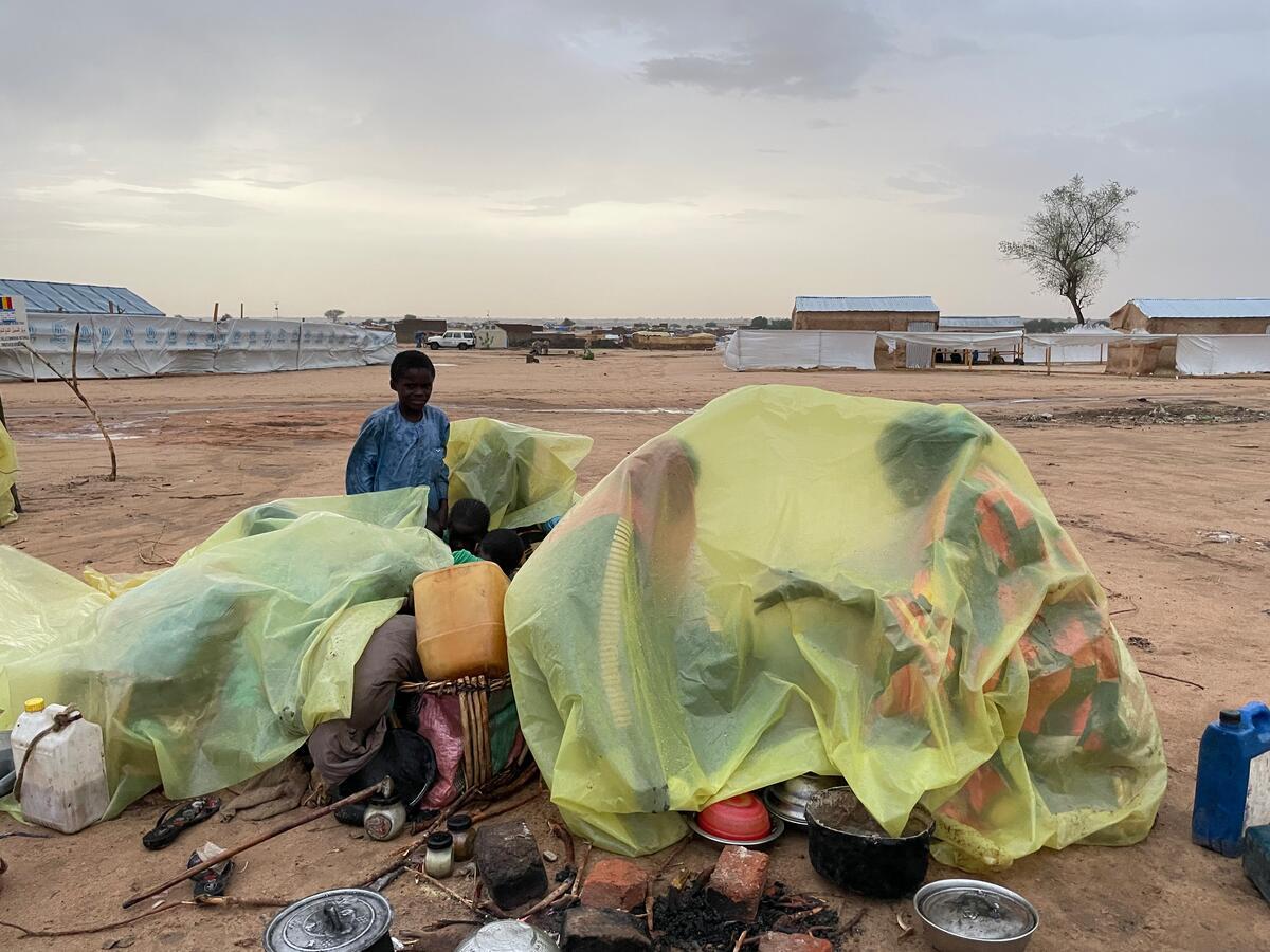 Refugees use plastic sheets to shelter from the rain at a spontaneous site for new arrivals from Sudan in Adre, eastern Chad.