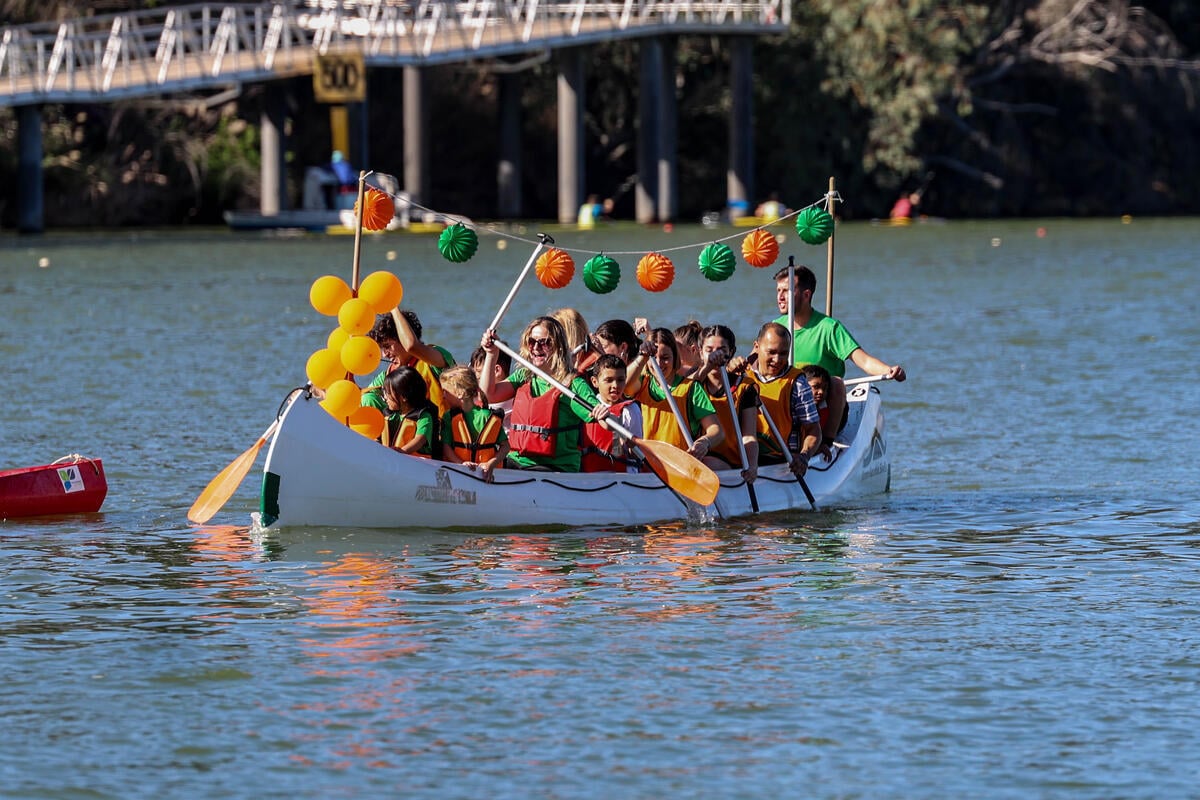 Men, women and children paddle a canoe decorated with green and orange paper lanterns and balloons.