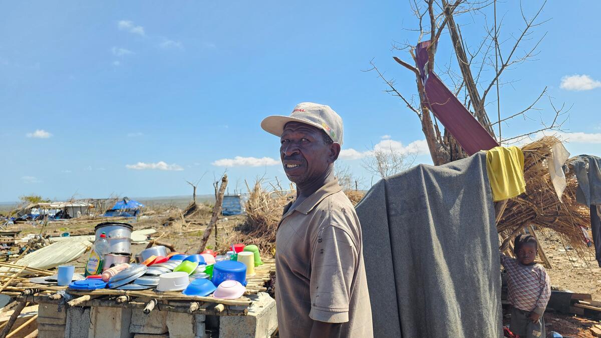 A man in a baseball cap looks out over the devastation caused by a cyclone.