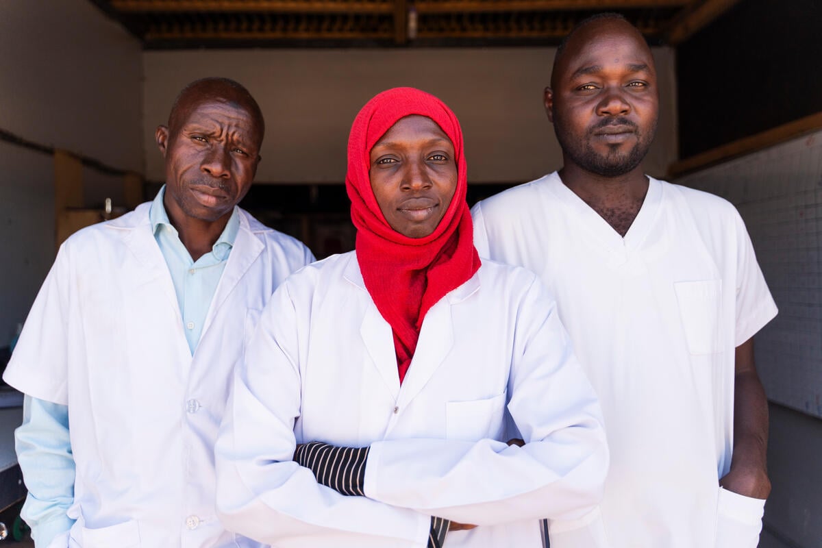 Three medical staff look at the camera, looking serious.