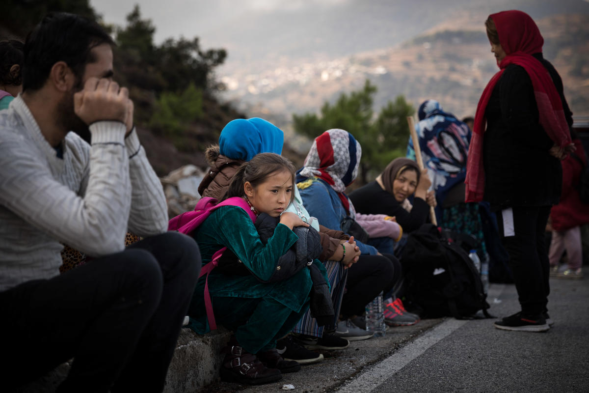 Men, women and children wait by the side of the road in Greece