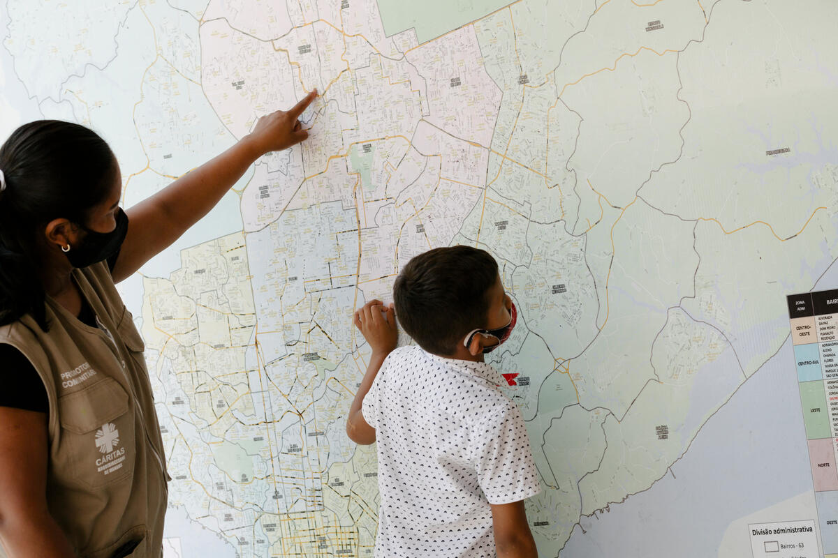 Lucetti and her 8-year-old Keiver examine a giant map of Manaus that hangs in her workplace, the UNHCR partner Caritas.