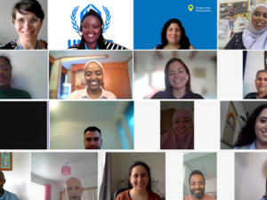 A group of 16 people on a zoom call smile to the camera.